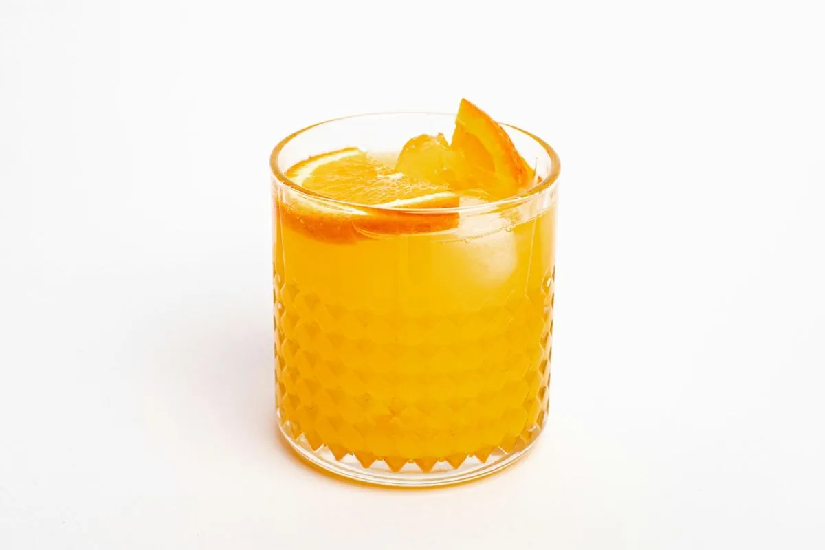A glass of fresh orange juice with a slice of orange on the rim